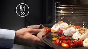 Person taking out baking tray from oven